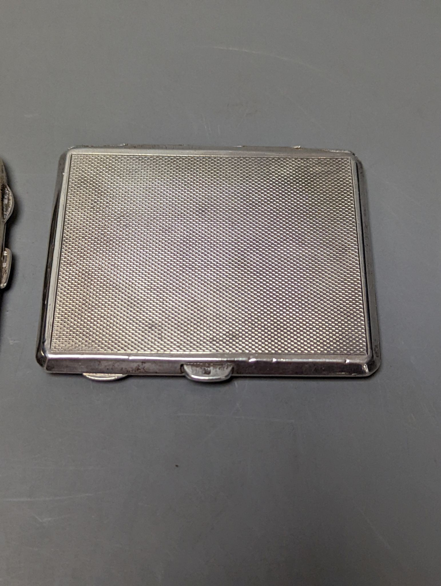 A silver cigarette case, an Austro Hungarian white metal box and a silver cigarette case with panel decorated with a topless lady, 77mm, gross weight 172 grams.